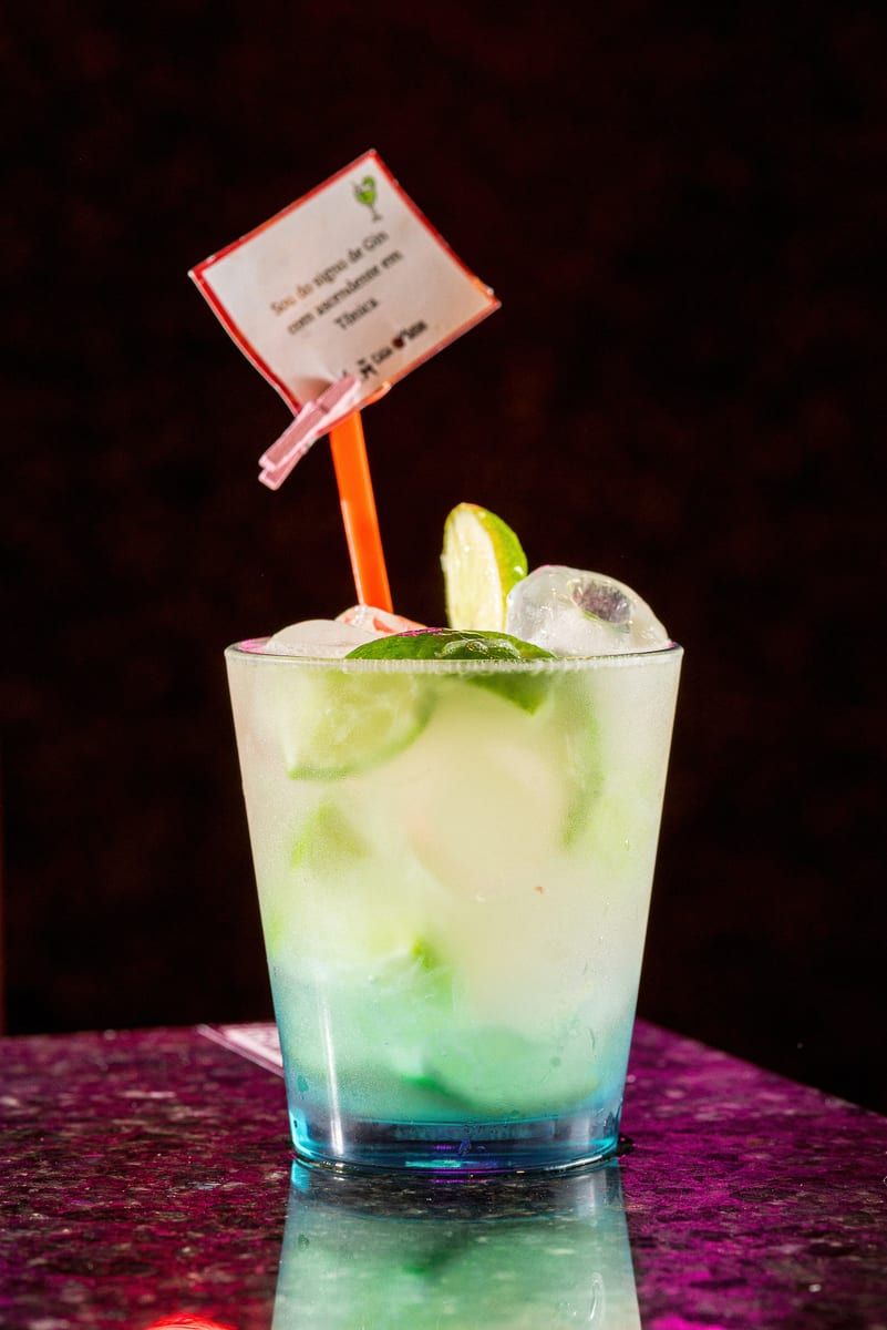 Copo baixo de caipirinha com gomos de limão e gelo, sobre o granito escuro