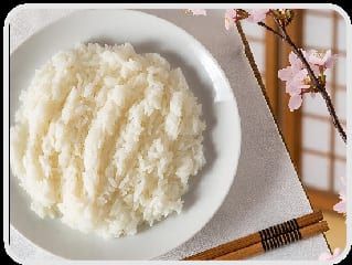 Tigela branca de arroz japonês soltinho, com hashi e um ramo de flores ao lado