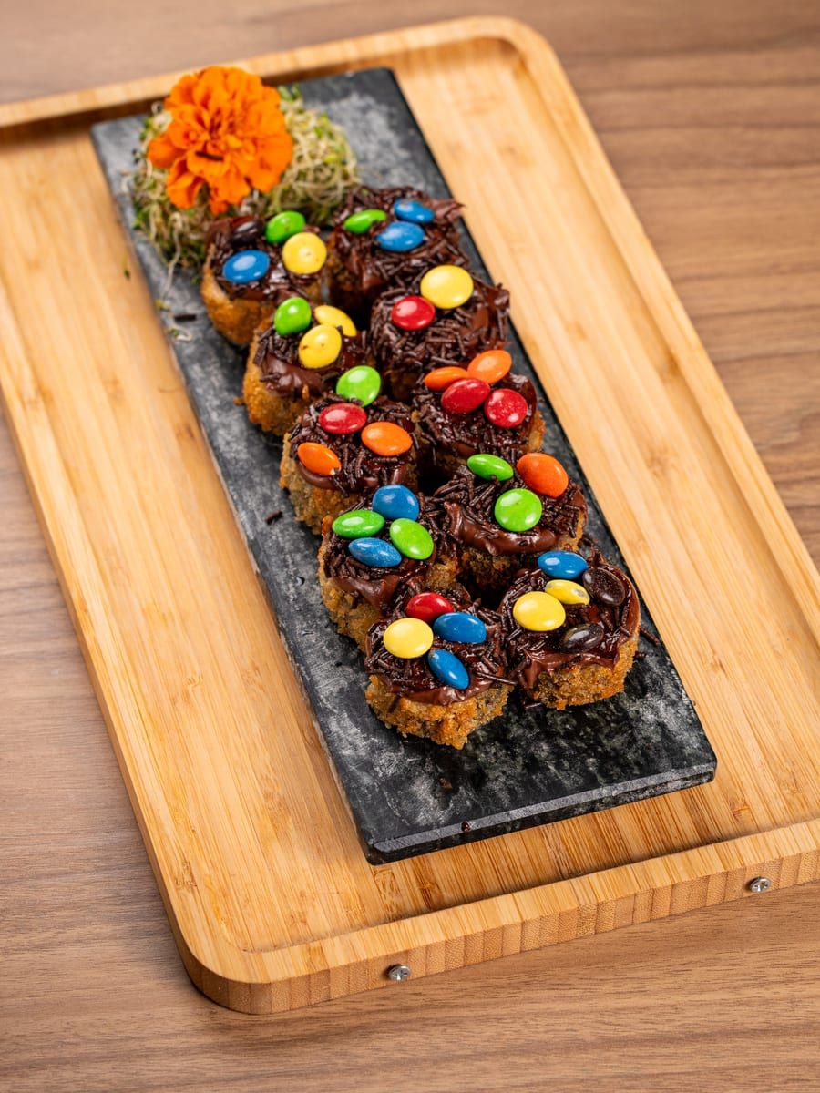 Peças empanadas cobertas de chocolate e confetes coloridos, na ardósia preta