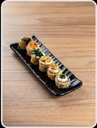 Fileira de hots empanados na travessa preta, alternando cobertura de cream cheese com crispy verde e crispy dourado
