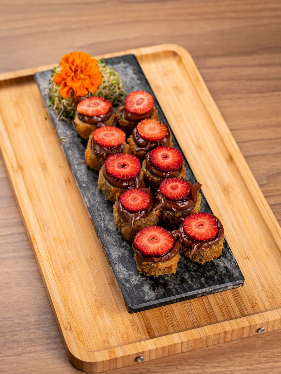 Peças empanadas cobertas de chocolate, cada uma com meio morango fresco por cima