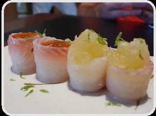 Joys enrolados em salmão ao lado de joys enrolados em peixe branco, em prato claro