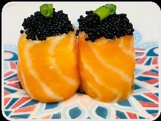 Dois joys enrolados em salmão com uma camada alta de ovas pretas no topo, em prato colorido