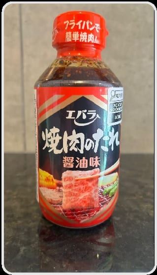 Garrafa de molho yakiniku japonês de rótulo vermelho, sobre a mesa