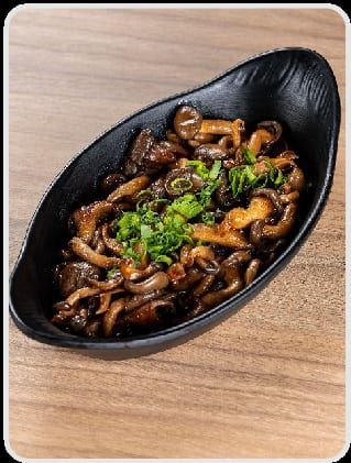 Cogumelos shimeji salteados com cebolinha picada, em travessa oval preta