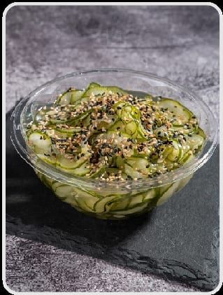 Lâminas finas de pepino marinado com gergelim, em bowl transparente sobre ardósia