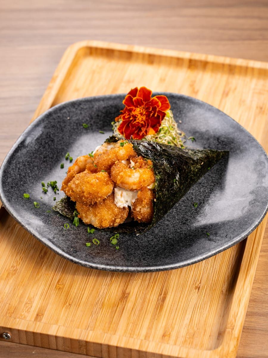 Temaki em cone de alga com camarões empanados saindo pela boca do cone
