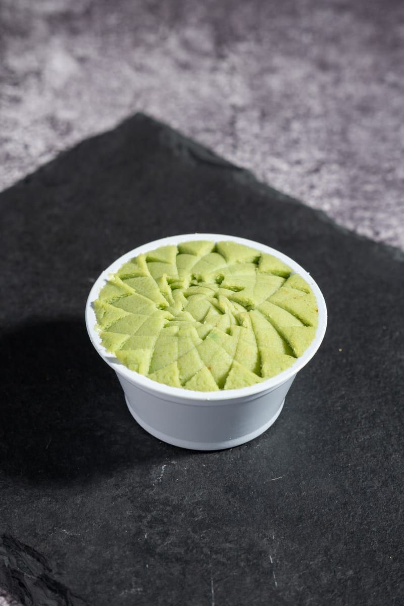 Potinho branco com pasta de wasabi verde raiada, sobre pedra de ardósia
